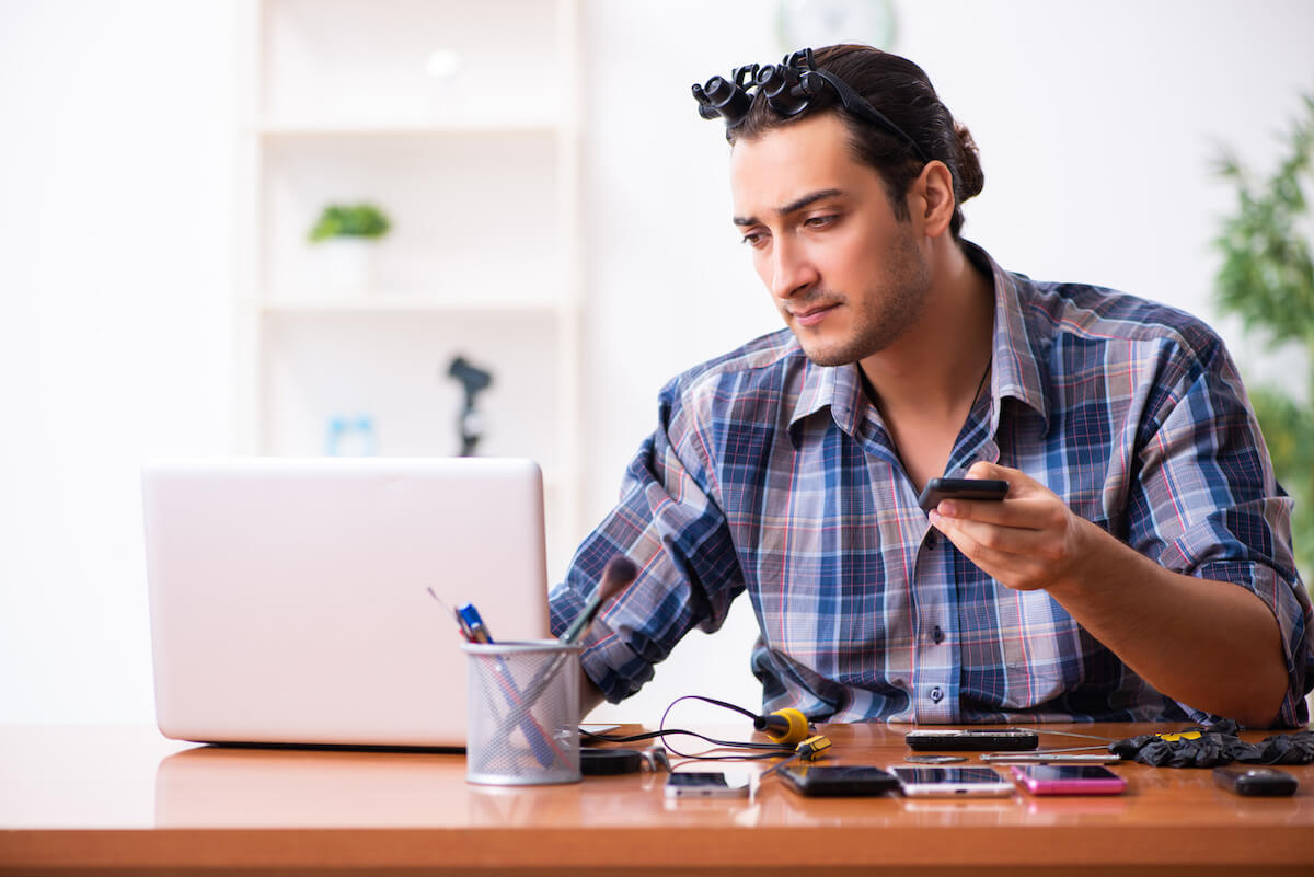Technician using a laptop and holding a phone